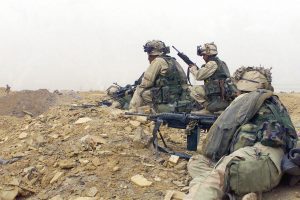 Armed with an FNMI 5.56mm M249 Squad Automatic Weapon (SAW), US Marine Corps (USMC) troops from Charlie Company, 1st Battalion, 5th Marines, 1st Marine Division out of Camp Pendleton, California move to protected positions, from which they can engage the enemy during a firefight in support of Operation IRAQI FREEDOM.