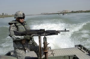 US Army (USA) Master Sergeant (MSG) Nardo Dedicatoria mans a mounted M60 7.62 mm Machine Gun on a riverboat during a patrol on the Euphrates River near Al Smarqkia, Iraqi (IRQ), in support of Operation IRAQI FREEDOM.
